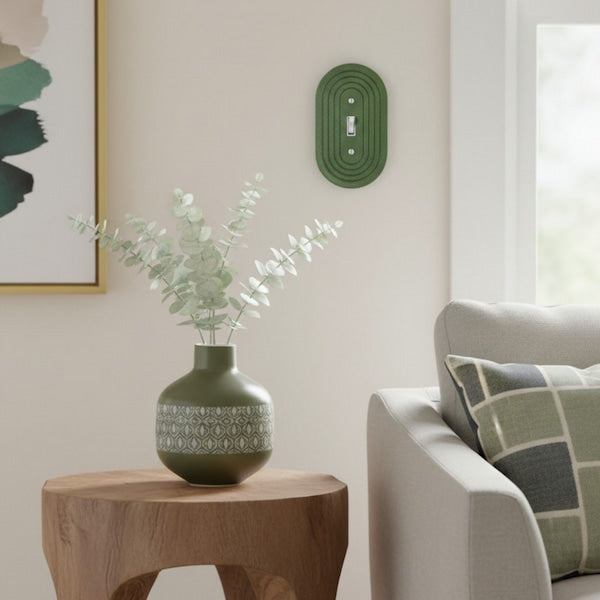 Green vase with eucalyptus on a wooden side table in a living room.